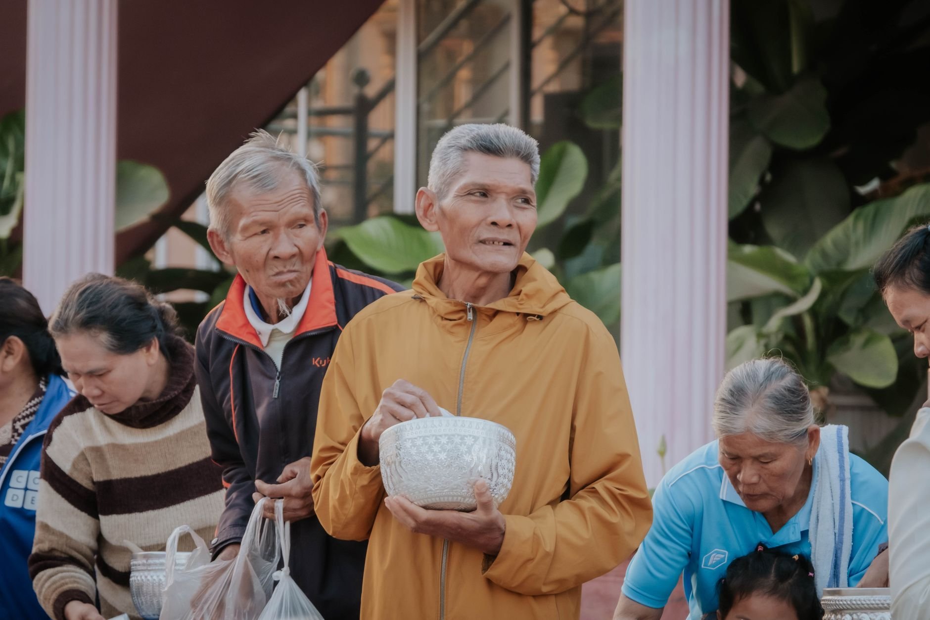 Elderly people in a community gathering, sharing gifts outdoors with a warm communal spirit.