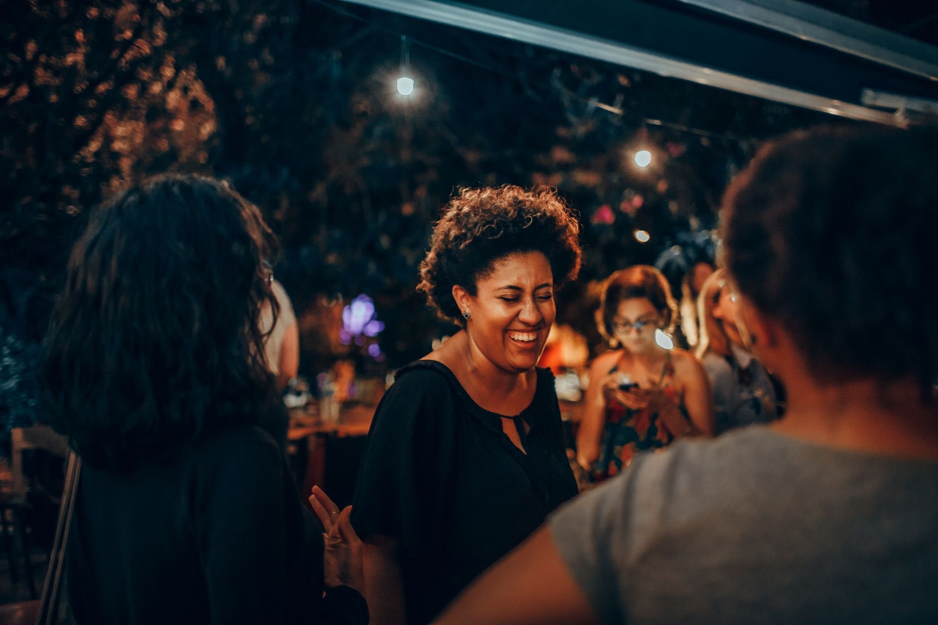 Group of friends enjoying a lively outdoor evening gathering under lights.